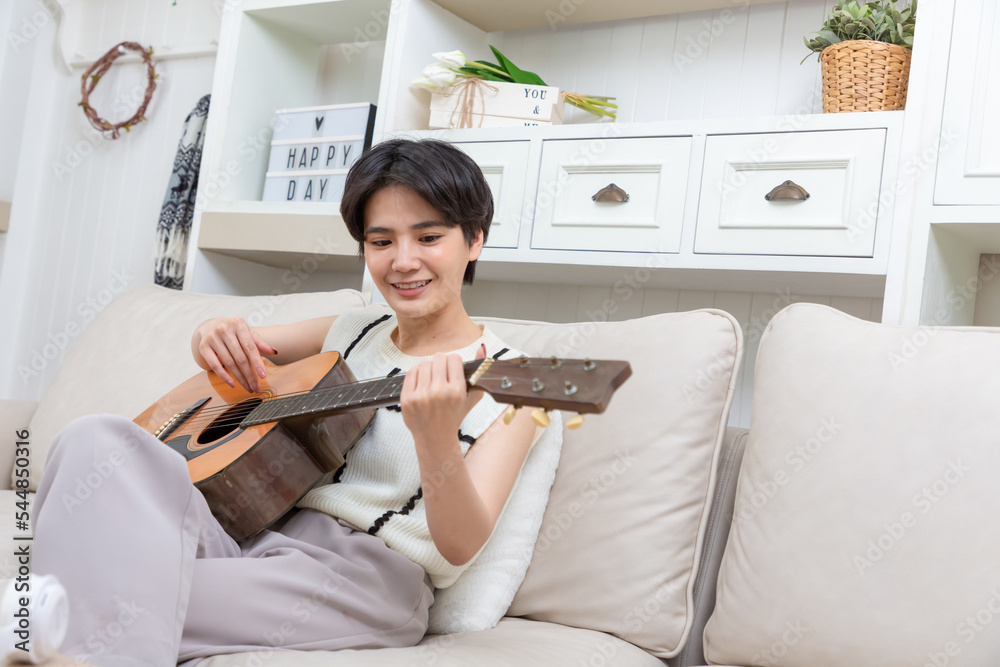 在家弹原声吉他乐器的顽皮亚洲女人，年轻的亚洲音乐家女孩生活