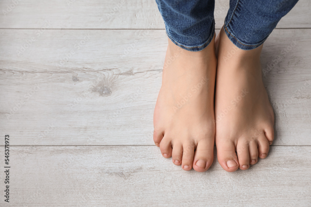 Female bare feet on wooden floor, closeup