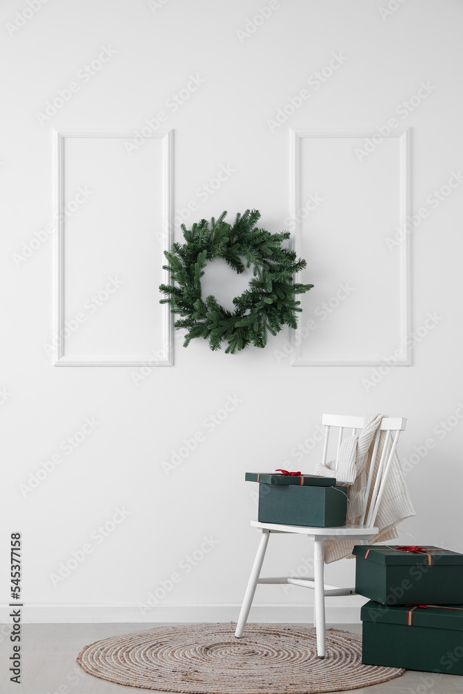 Chair with presents and Christmas wreath hanging on light wall