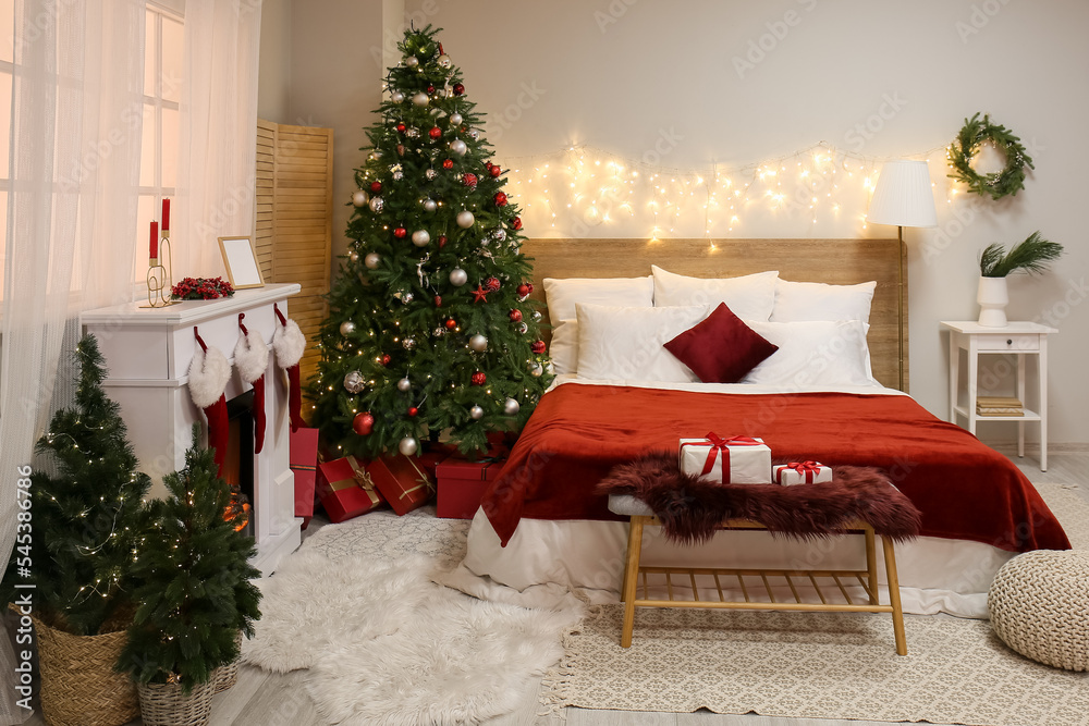 Interior of bedroom with glowing lights, Christmas trees and fireplace