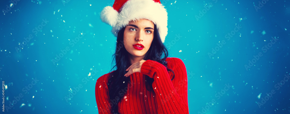 Beautiful young woman with a Santa hat in snowy night