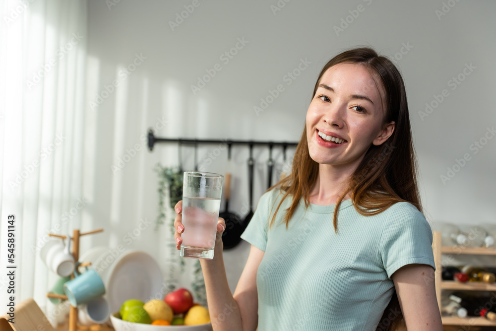 高加索妇女在家里厨房里喝一杯水的肖像。