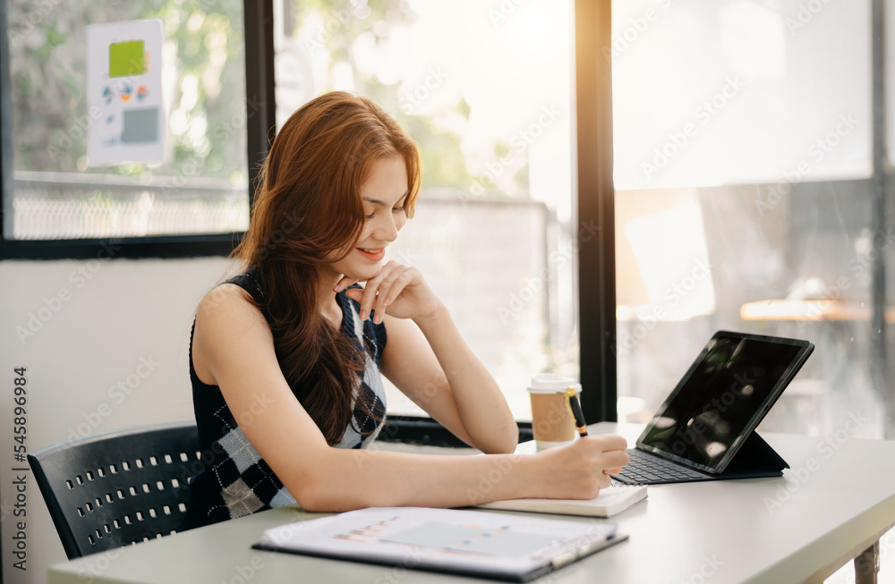 Asian female university student concentrating on her online classroom with tablet and laptop