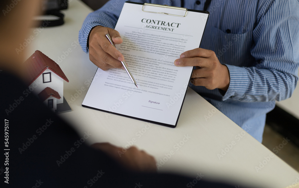 The real estate agent explaining the terms in the legal real estate agreement contract document, wai