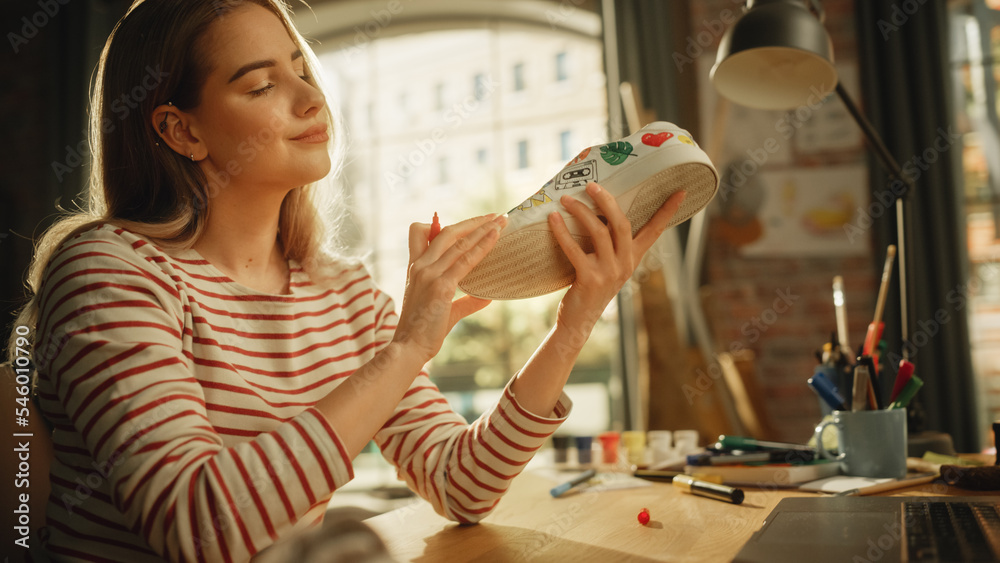 Work In Creative Space: Smiling Female Artist Renovating Sneakers in front of Laptop Computer. Fashi