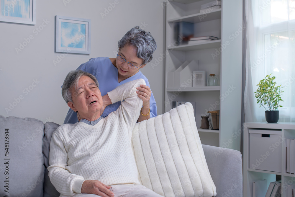 Asian old senior elderly husband sitting on sofa having problem with suffer backache painful shoulde