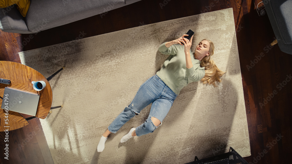 Apartment: Young Woman Lying on a Living Room Floor, Using Smartphone. Girl Relaxes at Home Freelanc