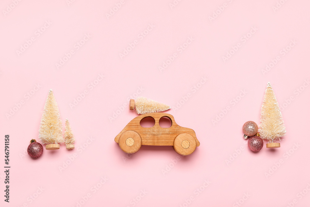 Toy car with Christmas trees and balls on pink background