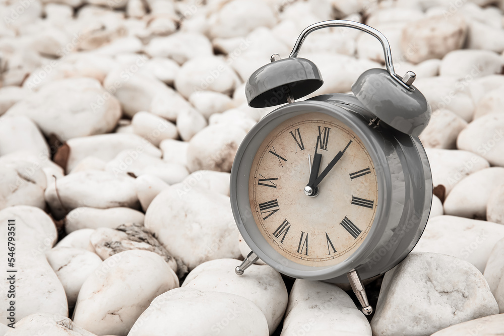 Vintage alarm clock on white stones, closeup