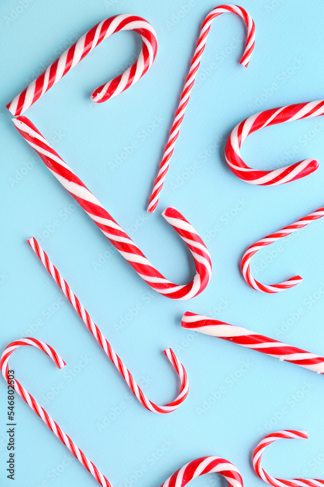 Composition with sweet candy canes on color background