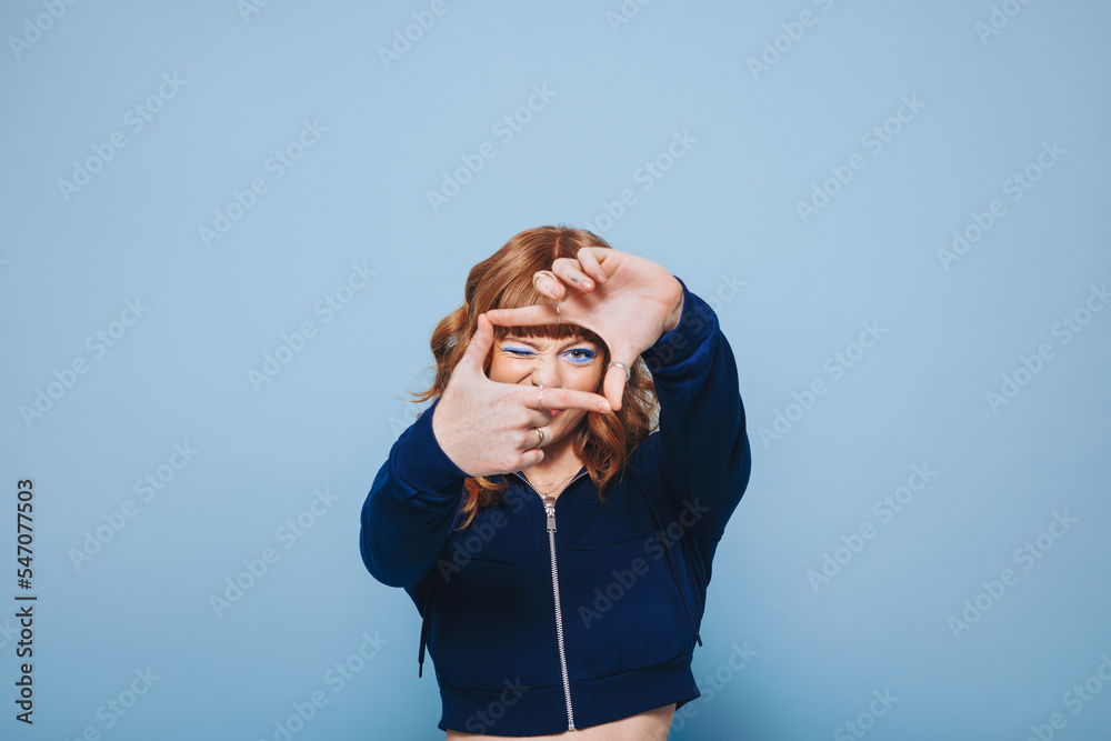 Young woman making a finger frame while standing in a studio