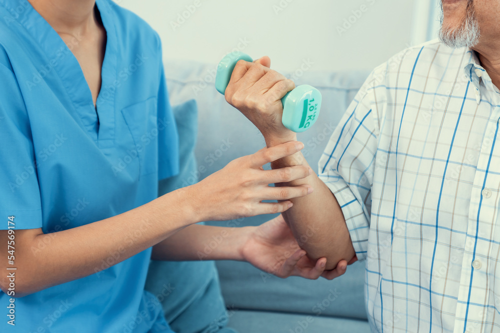 Contented senior patient doing physical therapy with the help of his caregiver. Senior physical ther