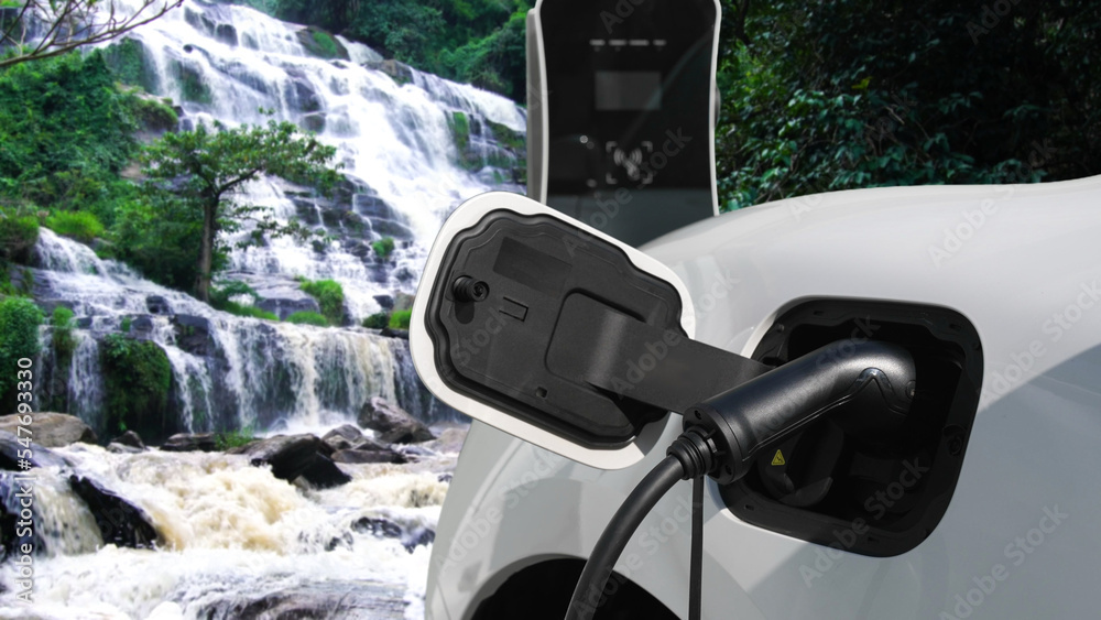 Electric car charging energy from charging station in the natural scenery, waterfall and stream back