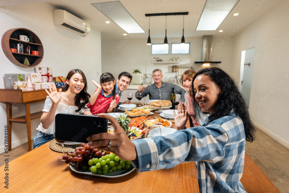 Multi-ethnic family take a selfies while having dinner party in house.