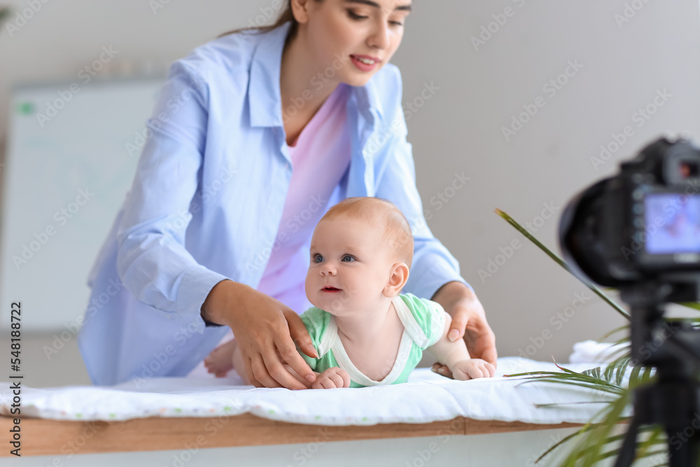 带着小婴儿的年轻女子在家录制视频课程