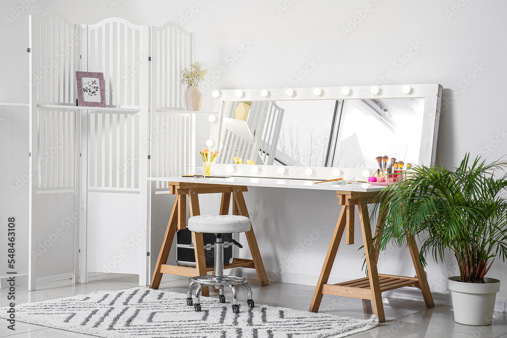 Modern workplace of makeup artist with mirror and decorative cosmetics in light room