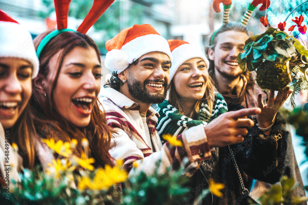 Happy group of friends having fun at Christmas Market souvenir shop - Cheerful young tourists enjoyi