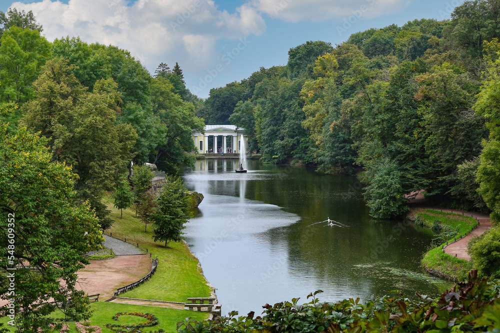 View of beautiful park with river, fountain and green trees