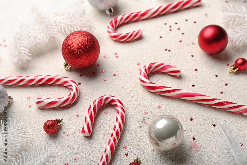 Composition with sweet candy canes and Christmas balls on light background