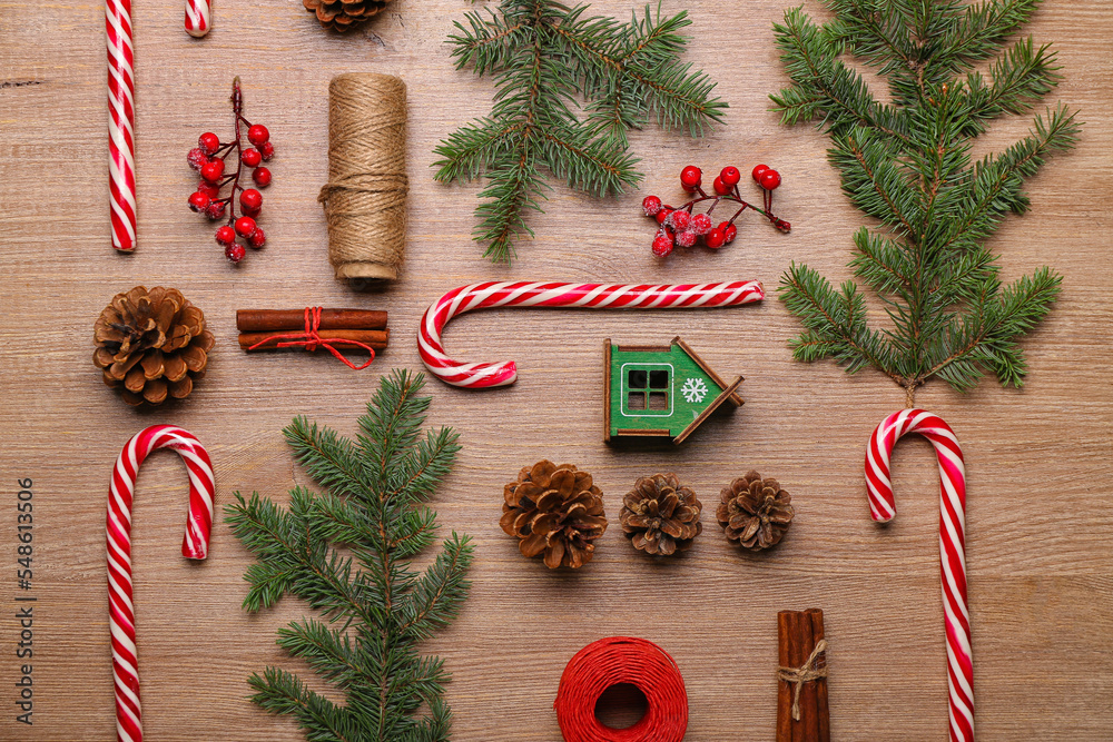 Composition with sweet candy canes, fir branches and cones on wooden background