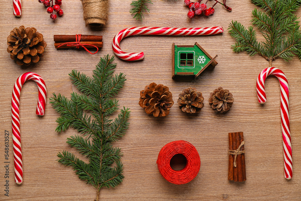 Composition with sweet candy canes, fir branches and cones on wooden background