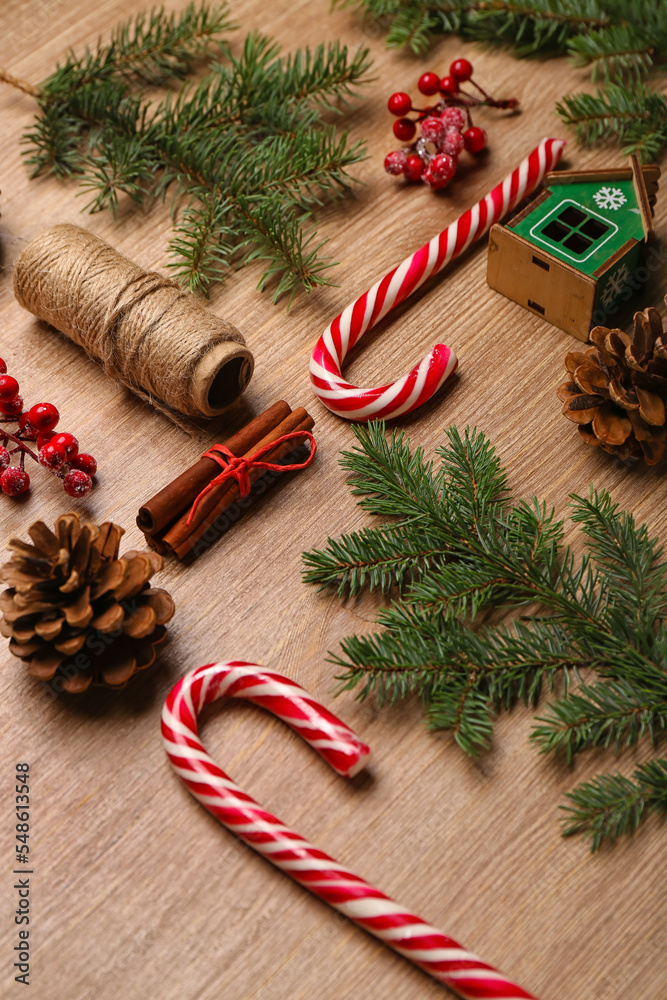 Composition with sweet candy canes, fir branches and cones on wooden background