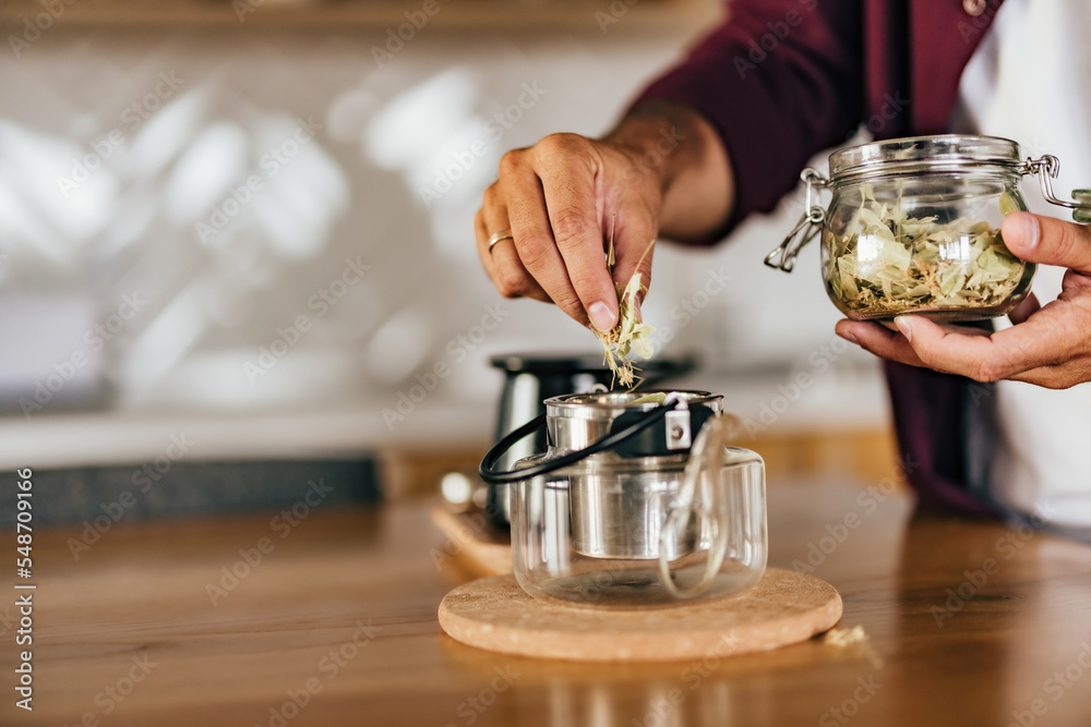 一名男子将草药放入锅中，制作茶壶的侧视图。