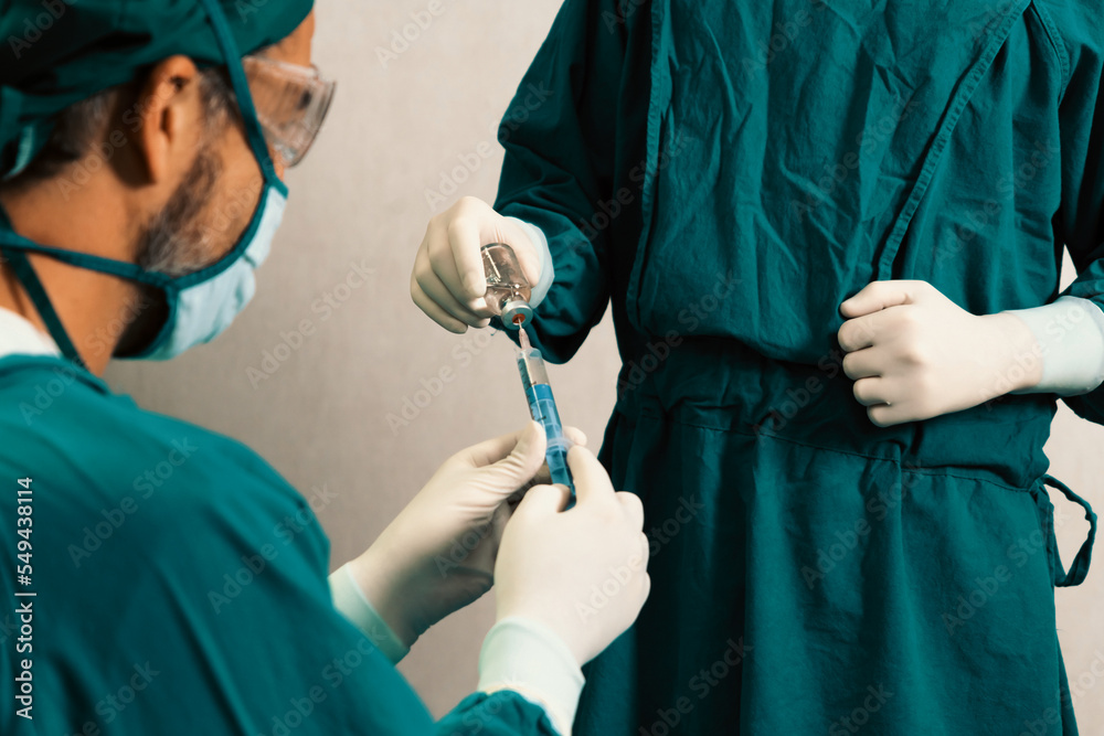 Surgeon fill syringe from medical vial for surgical procedure at sterile operation room with assista