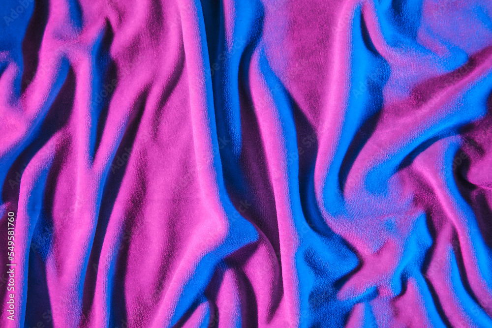 Soft crumpled fabric in neon light as background