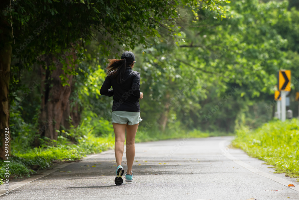 Asian  woman in sportswear Jogging running  at park in sunshine on beautiful  day