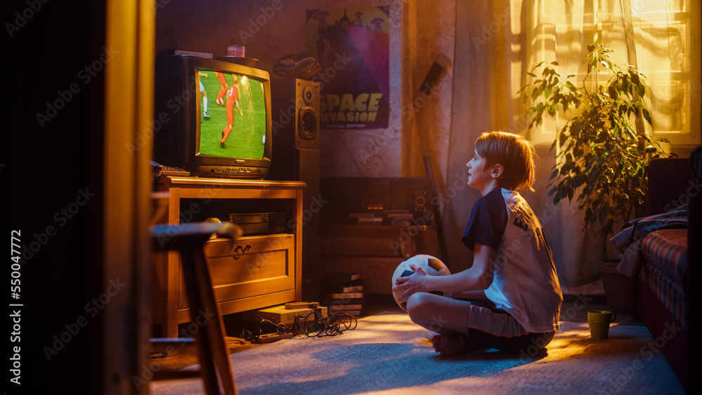 Young Sports Fan Watches a Soccer Match on Retro TV in His Room with Dated Interior. Boy Supporting 