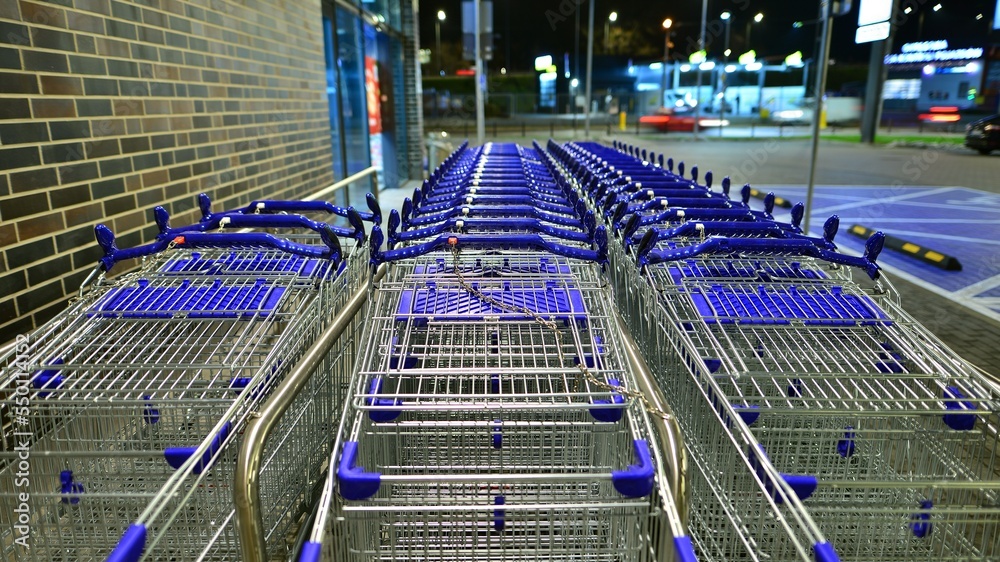 Row of shopping carts outside market in night.