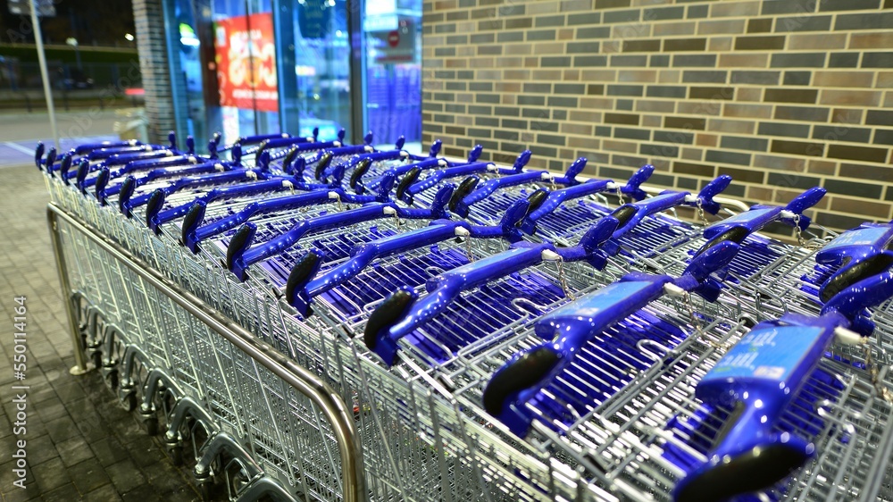 Row of shopping carts outside market in night.