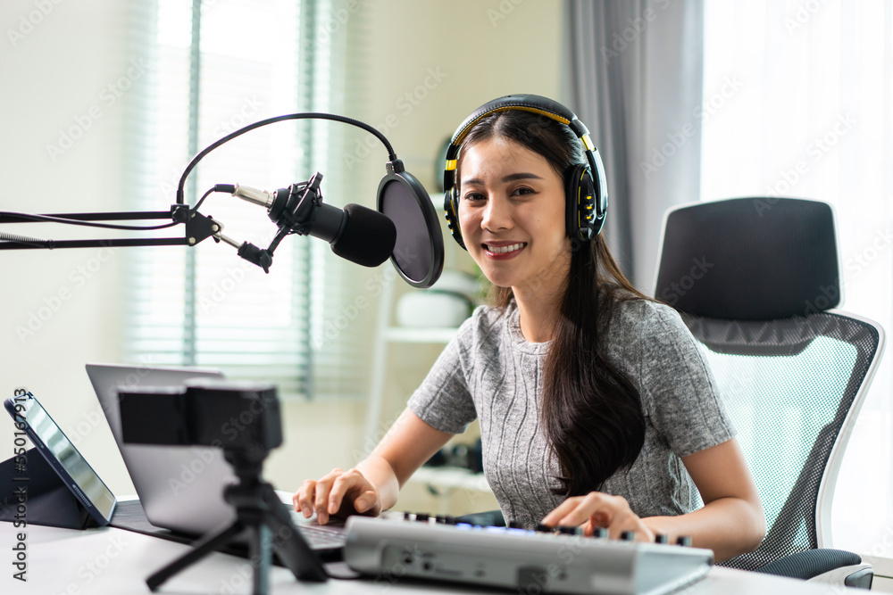 Asian attractive audio DJ woman speaks into microphone to broadcasting.