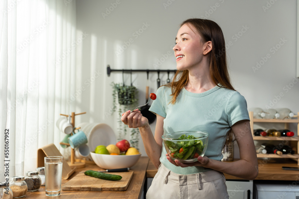 高加索年轻女子在家的厨房里吃健康的绿色沙拉。