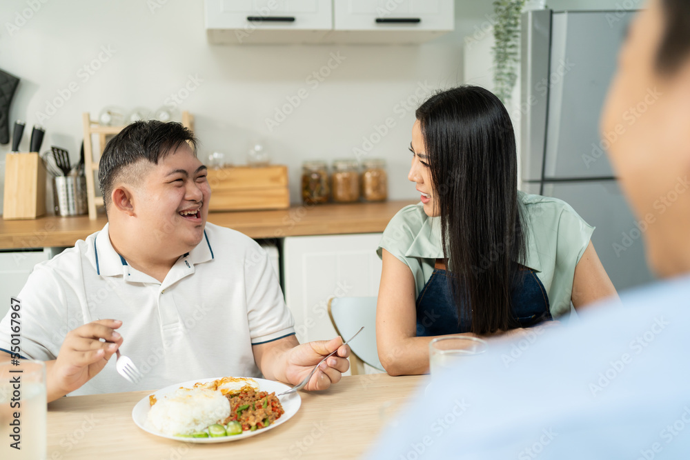 Asian happy family, mature parent having breakfast with son in kitchen.