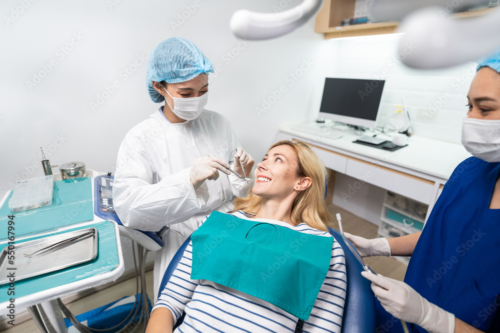 Female dentist examine tooth to Caucasian girl at dental health clinic