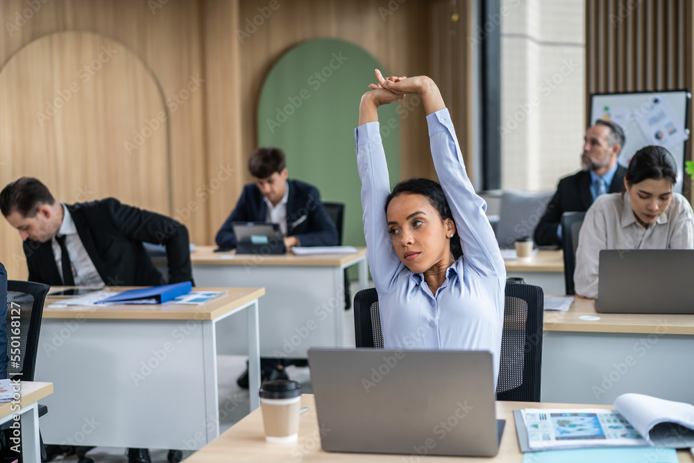 Young Latino businesswoman stretching body while working in the office. 