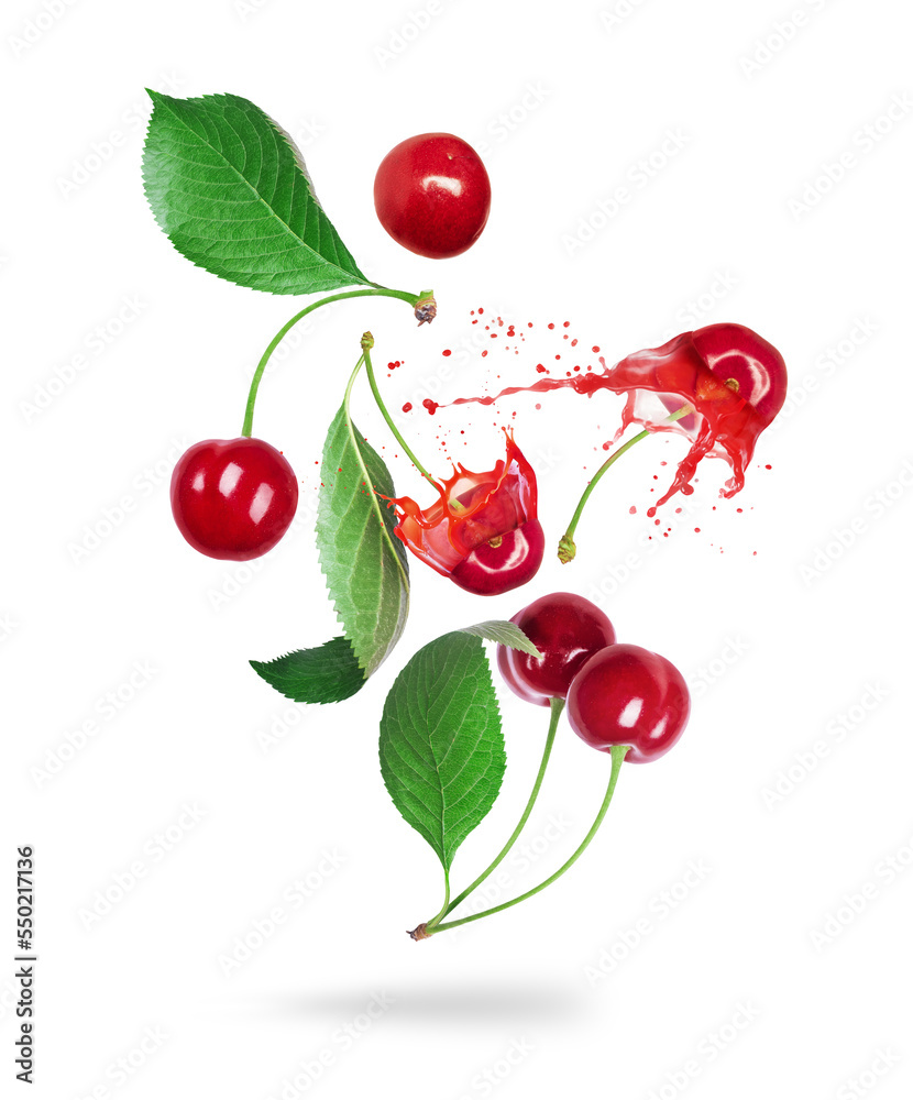 Whole and sliced cherries with juice splashes in the air isolated on a white background