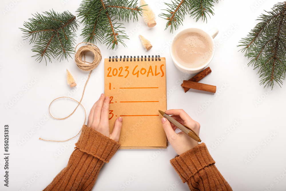 Woman making to-do list for year 2023 at white table, top view