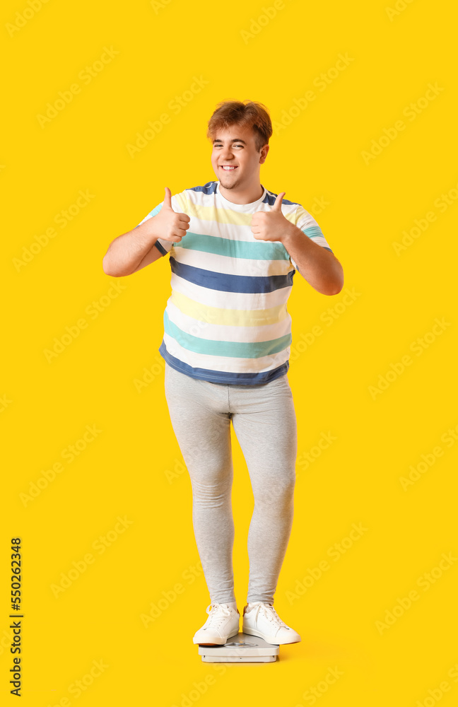 Young overweight man showing thumbs-up on yellow background