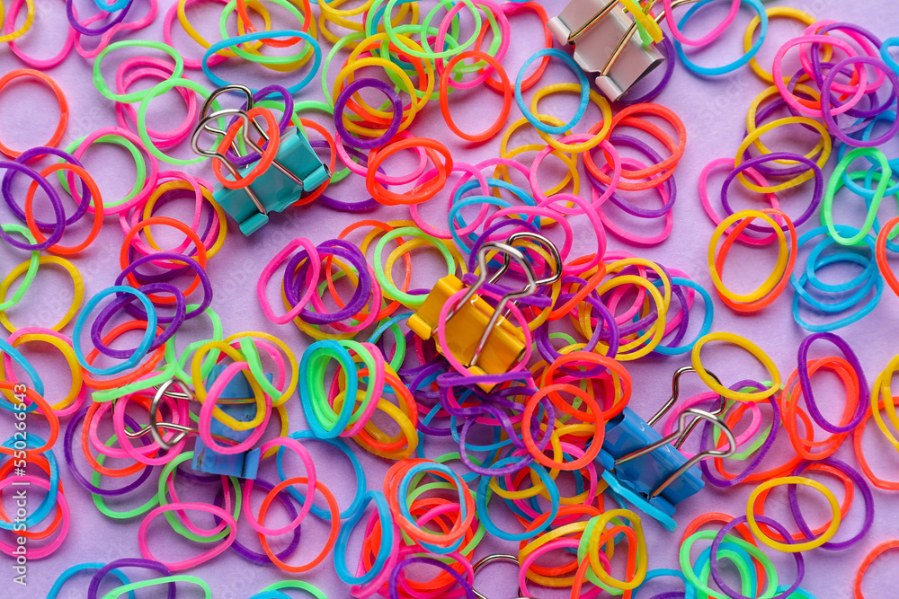 Colorful rubber bands and paper clips on lilac background