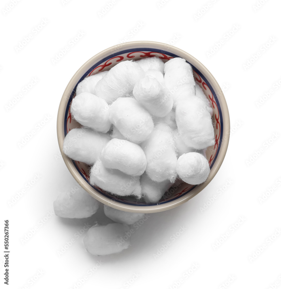 Bowl of soft cotton balls on light background