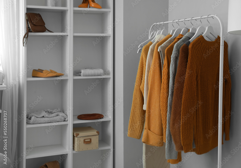 Rack with knitted sweaters in modern room