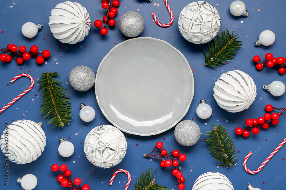 Composition with empty plate, fir branches, Christmas decorations and candy canes on color backgroun