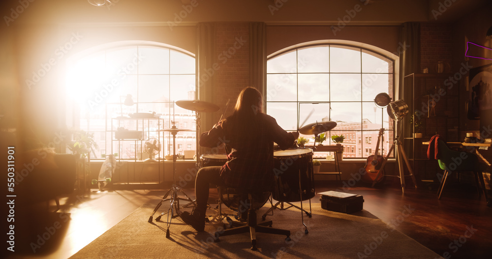 Person Sitting with Their Back to Camera and Playing Drums During a Band Rehearsal in a Loft Studio 