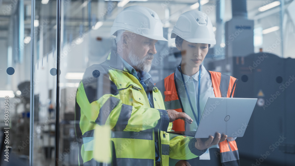 Two Professional Heavy Industry Engineers Wearing Safety Uniform and Hard Hats Discussing Industrial