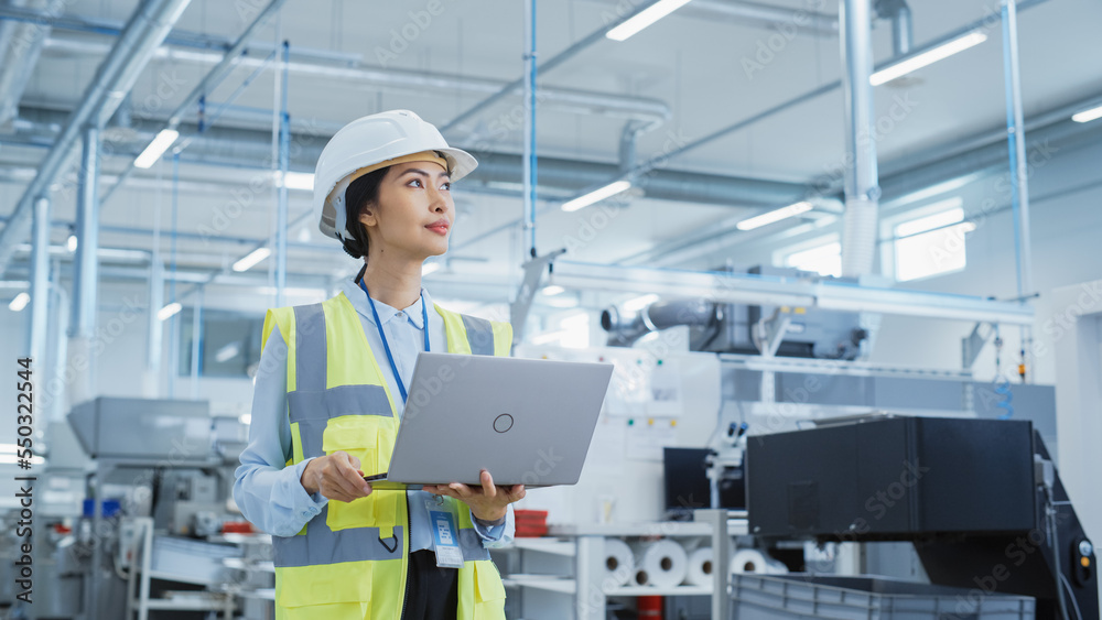 Portrait of a Happy Asian Female Engineer in Hard Hat Standing and Using Laptop Computer at Electron