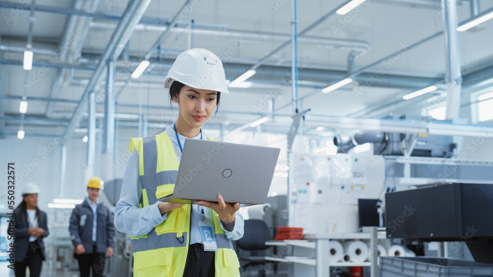 Portrait of a Happy Asian Female Engineer in Hard Hat Standing and Using Laptop Computer at Electron