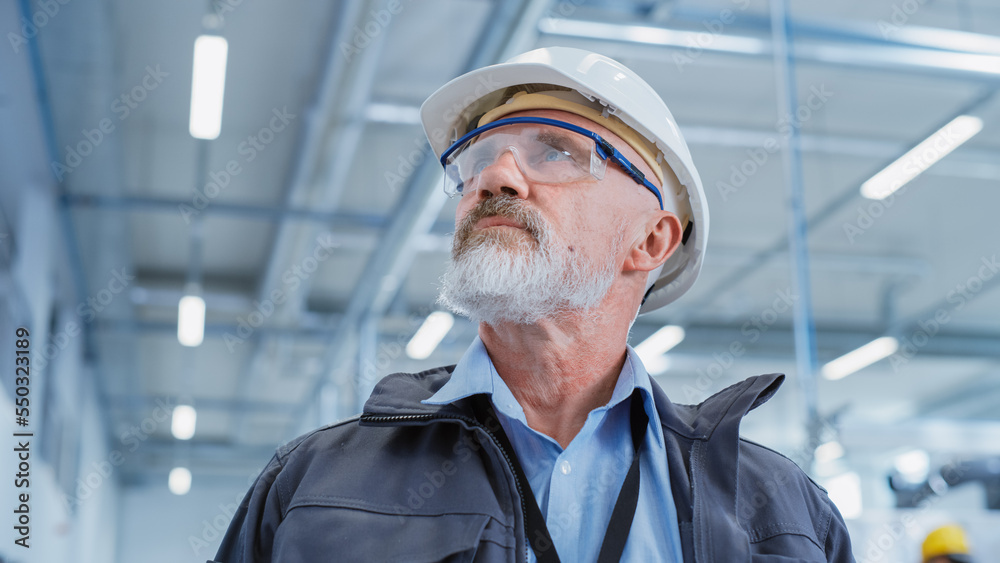 Portrait of a Middle Aged, Successful Male Engineer in White Hard Hat and Safety Glasses, Standing a